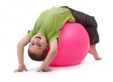 young child in fundamental movement phase, stretching on a pink yoga ball