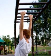 child utilizing their upper body strength on the monkey bars