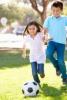 two children practicing their agility while playing soccer at the park