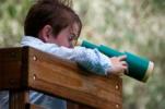 child utilizing their visual perception with a playground telescope