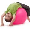 young child in fundamental movement phase, stretching on a pink yoga ball